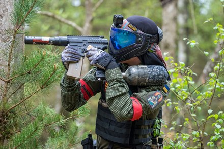 Spiller med trykflaske på skulderen og rødt armbånd sigter ved en grantykning