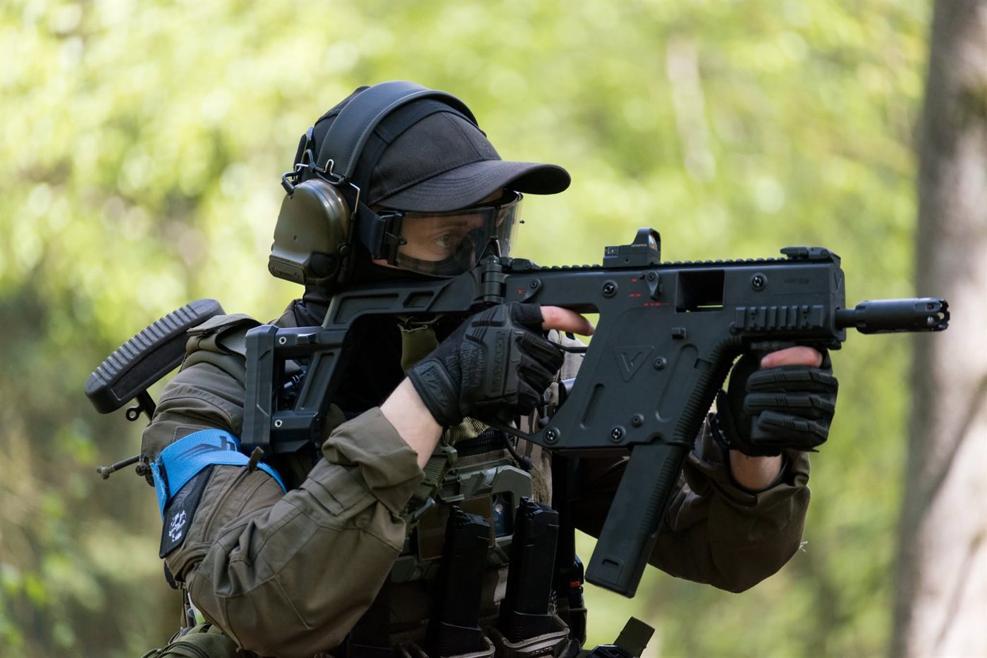 Spiller med Kriss Vector og blåt armbånd sigter mellem træerne