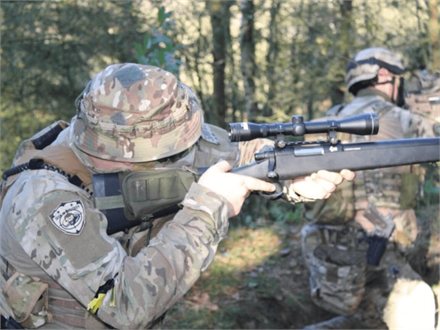 Spiller med bolt action-riffel og kikkertsigte i efterårsskoven